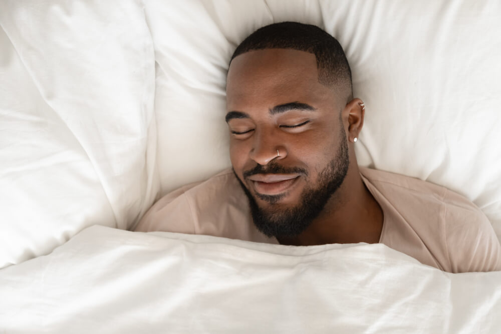 A Happy Man Sleeping in Comfortable White Bed