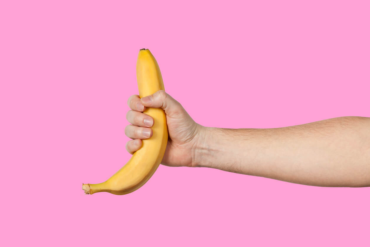 Banana as a Symbol of Male Penis in Hand on a Yellow Background Hidden by Censorship
